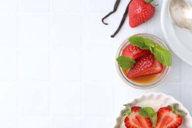 Photo of Tasty panna cotta with caramel, strawberries, mint and vanilla pods on white table, flat lay. Space for text