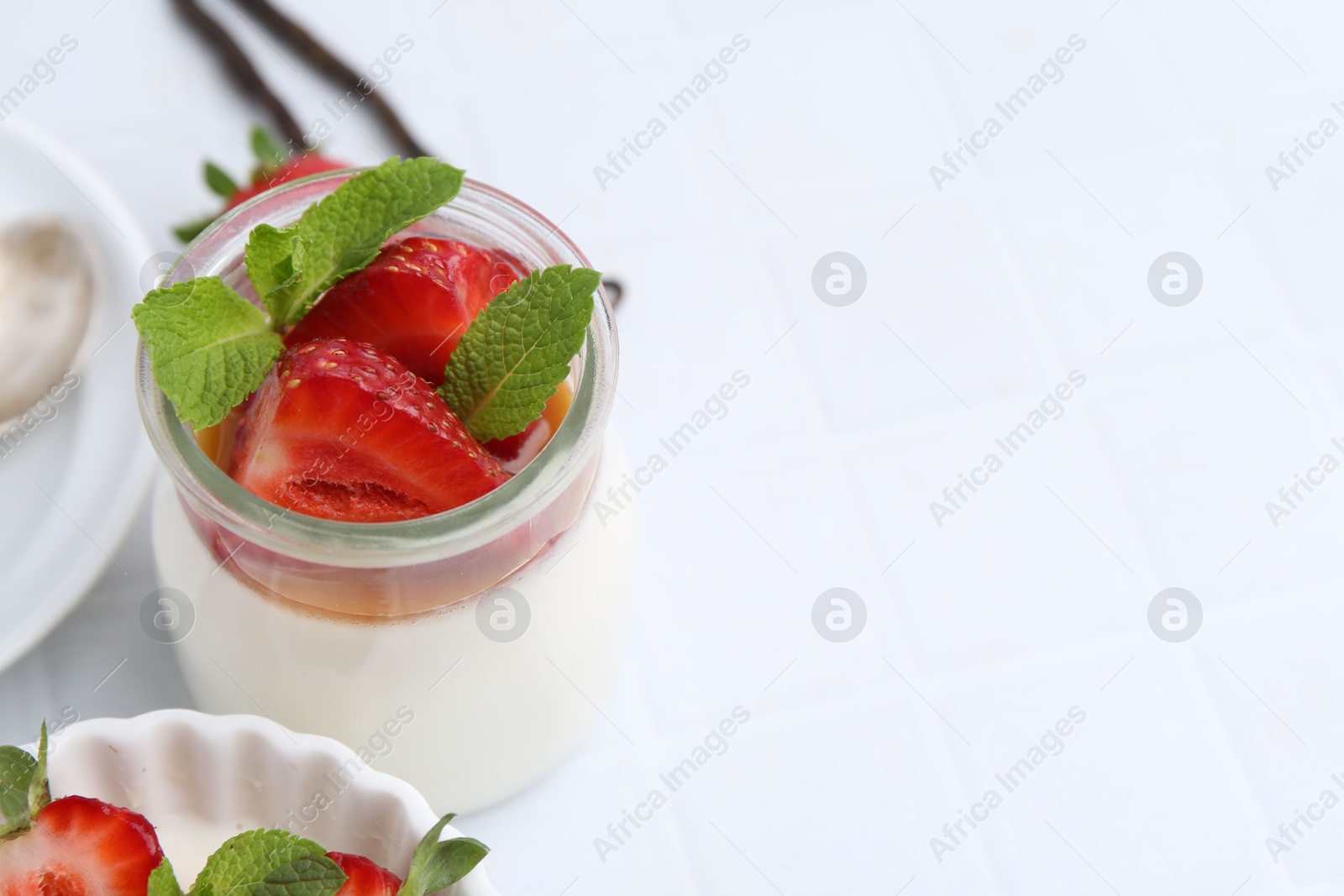 Tasty panna cotta with caramel, strawberries, mint and vanilla pods on white table, closeup. Space for text Photo of Tasty panna cotta with caramel, strawberries, mint and vanilla pods on white table, closeup. Space for text