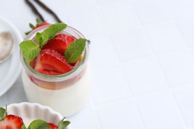 Photo of Tasty panna cotta with caramel, strawberries, mint and vanilla pods on white table, closeup. Space for text