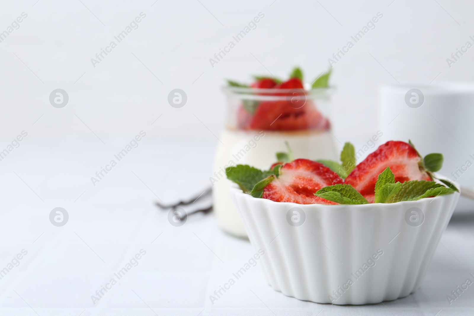 Tasty panna cotta with strawberries, mint and vanilla pods on white table, closeup. Space for text Photo of Tasty panna cotta with strawberries, mint and vanilla pods on white table, closeup. Space for text