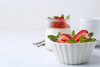 Photo of Tasty panna cotta with strawberries, mint and vanilla pods on white table, closeup. Space for text