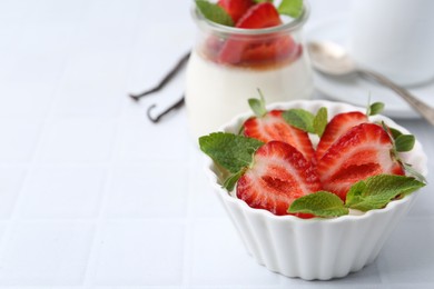 Photo of Tasty panna cotta with strawberries, mint and vanilla pods on white table, closeup. Space for text