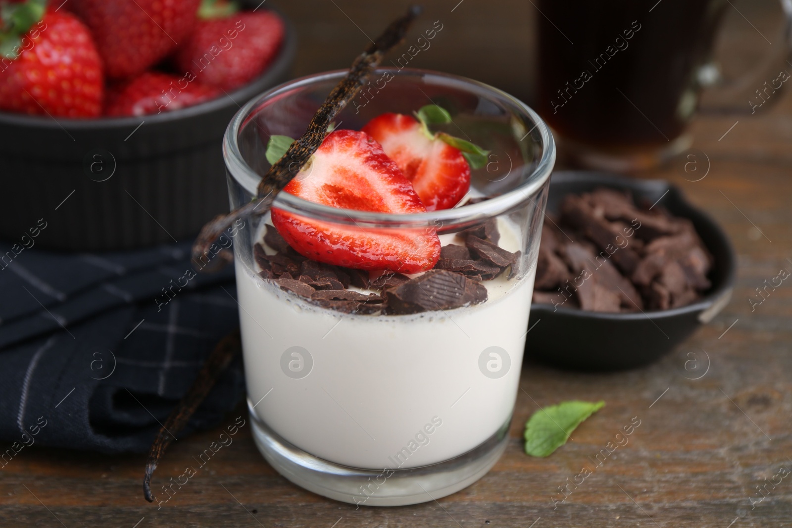 Tasty panna cotta with chocolate, strawberries, mint and vanilla pods on wooden table, closeup Photo of Tasty panna cotta with chocolate, strawberries, mint and vanilla pods on wooden table, closeup