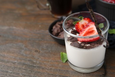 Photo of Tasty panna cotta with chocolate, strawberry, mint and vanilla pods on wooden table, closeup. Space for text