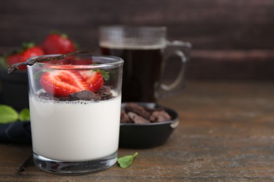 Photo of Tasty panna cotta with chocolate, strawberries, mint and vanilla pods on wooden table, closeup. Space for text