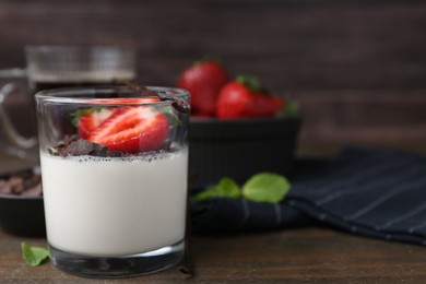 Photo of Tasty panna cotta with chocolate, strawberries, mint and vanilla pods on wooden table, closeup. Space for text