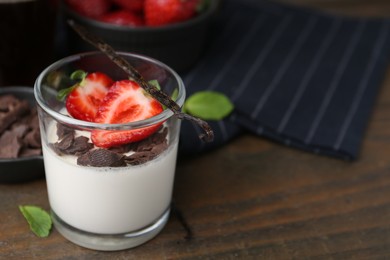 Photo of Tasty panna cotta with chocolate, strawberries, mint and vanilla pods on wooden table, closeup. Space for text