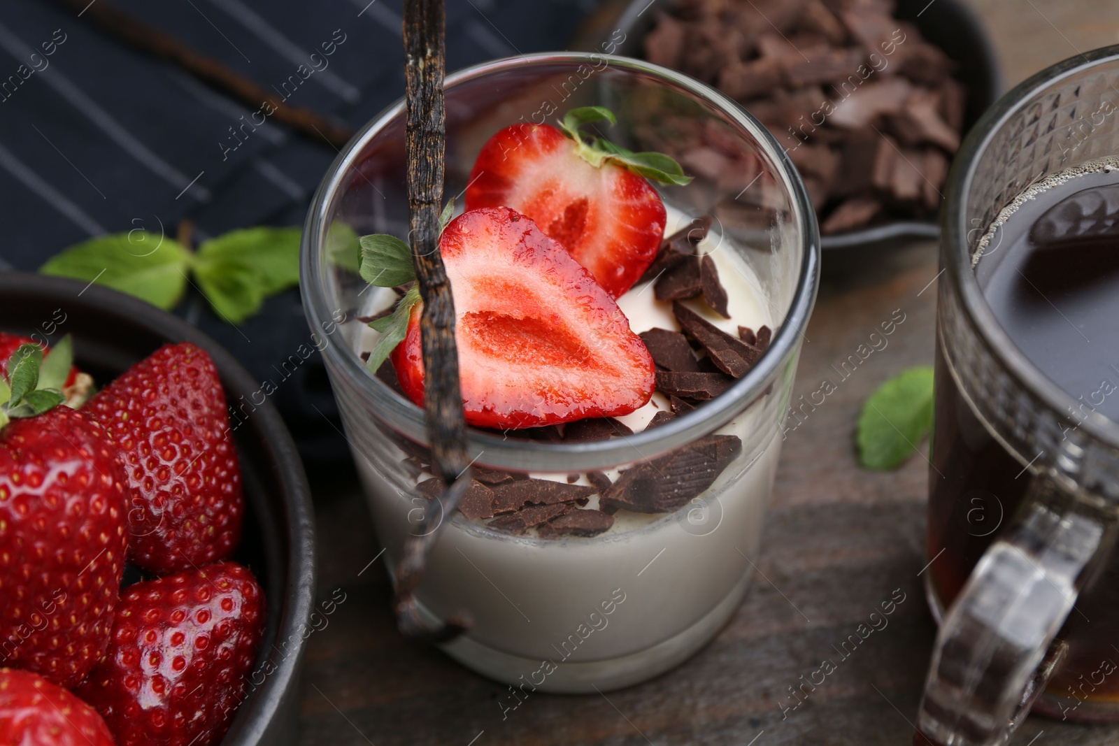 Tasty panna cotta with chocolate, strawberries, mint, vanilla pod and tea on wooden table, above view Photo of Tasty panna cotta with chocolate, strawberries, mint, vanilla pod and tea on wooden table, above view