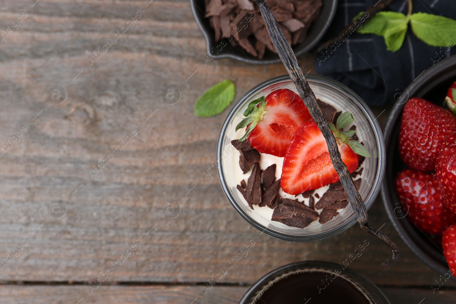 Tasty panna cotta with chocolate, strawberries, mint, vanilla pods and tea on wooden table, flat lay. Space for text Photo of Tasty panna cotta with chocolate, strawberries, mint, vanilla pods and tea on wooden table, flat lay. Space for text