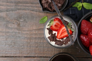 Photo of Tasty panna cotta with chocolate, strawberries, mint, vanilla pods and tea on wooden table, flat lay. Space for text