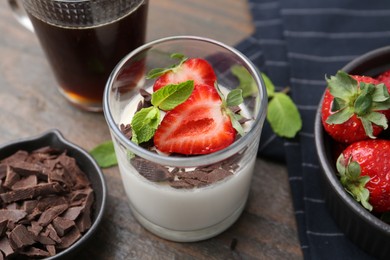 Photo of Tasty panna cotta with chocolate, strawberries, mint, vanilla pods and tea on wooden table, above view