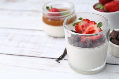 Photo of Tasty panna cotta with chocolate, strawberries and vanilla on white wooden table, closeup. Space for text