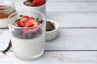 Photo of Tasty panna cotta with chocolate, strawberries and vanilla on white wooden table, closeup. Space for text
