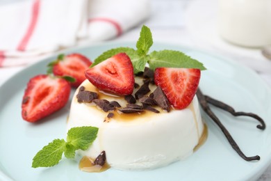 Photo of Tasty panna cotta with chocolate, strawberries, mint, caramel and vanilla pods on table, closeup