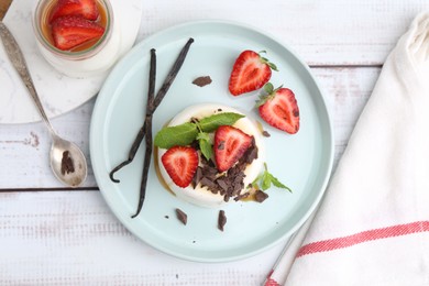 Photo of Tasty panna cotta with chocolate, strawberries, mint, caramel and vanilla on white wooden table, flat lay