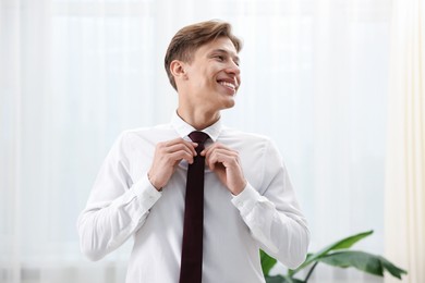 Photo of Man tying stylish brown necktie at home