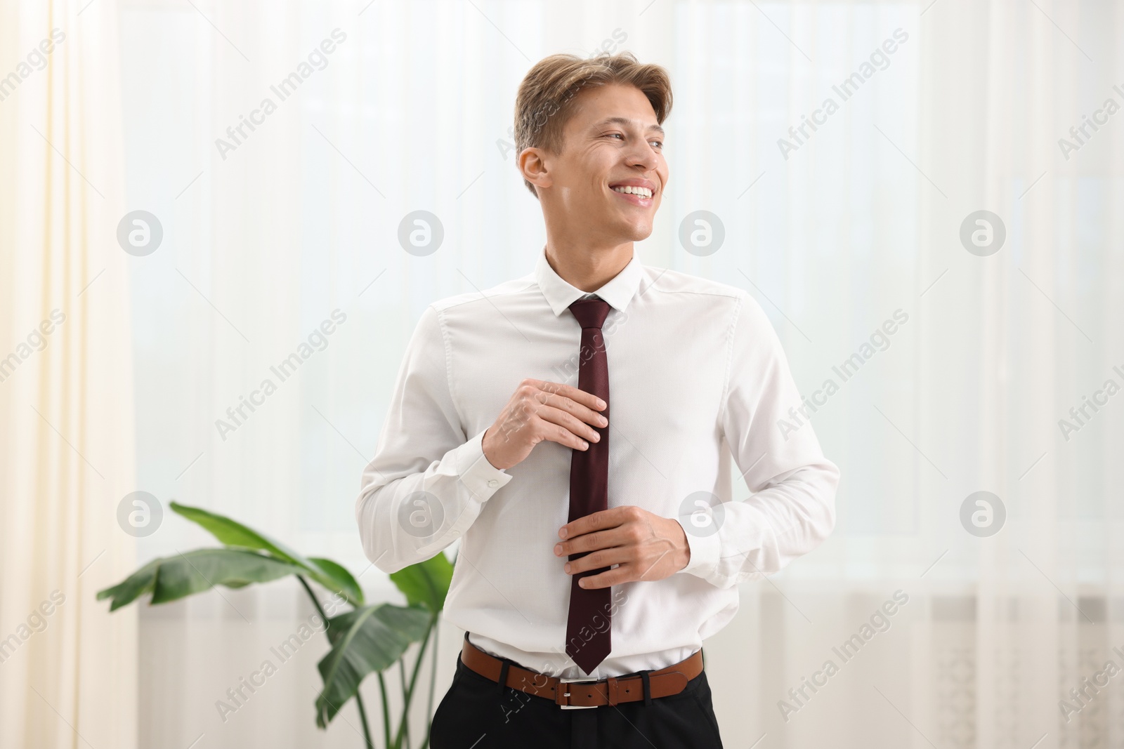 Photo of Man tying stylish brown necktie at home