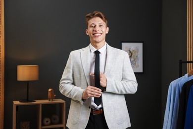 Photo of Man tying stylish black necktie at home
