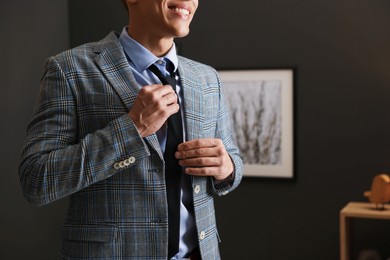 Photo of Man tying stylish necktie at home, closeup