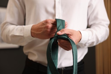 Photo of Man with stylish green necktie at home, closeup