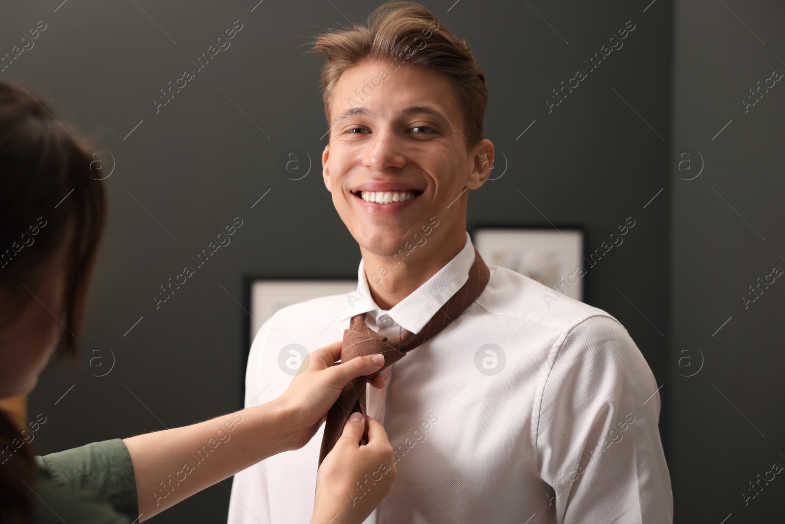 Photo of Woman tying man's necktie at home, closeup