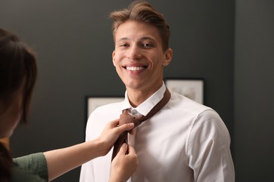 Photo of Woman tying man's necktie at home, closeup
