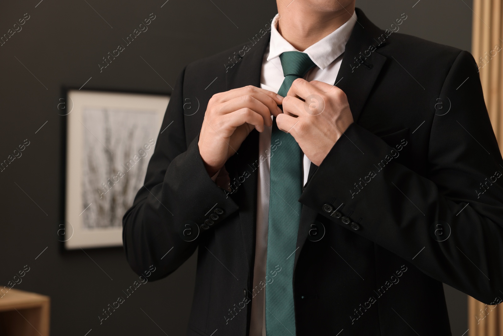 Photo of Man tying stylish necktie at home, closeup