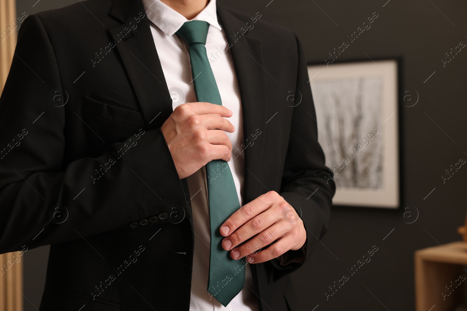Photo of Man tying stylish necktie at home, closeup