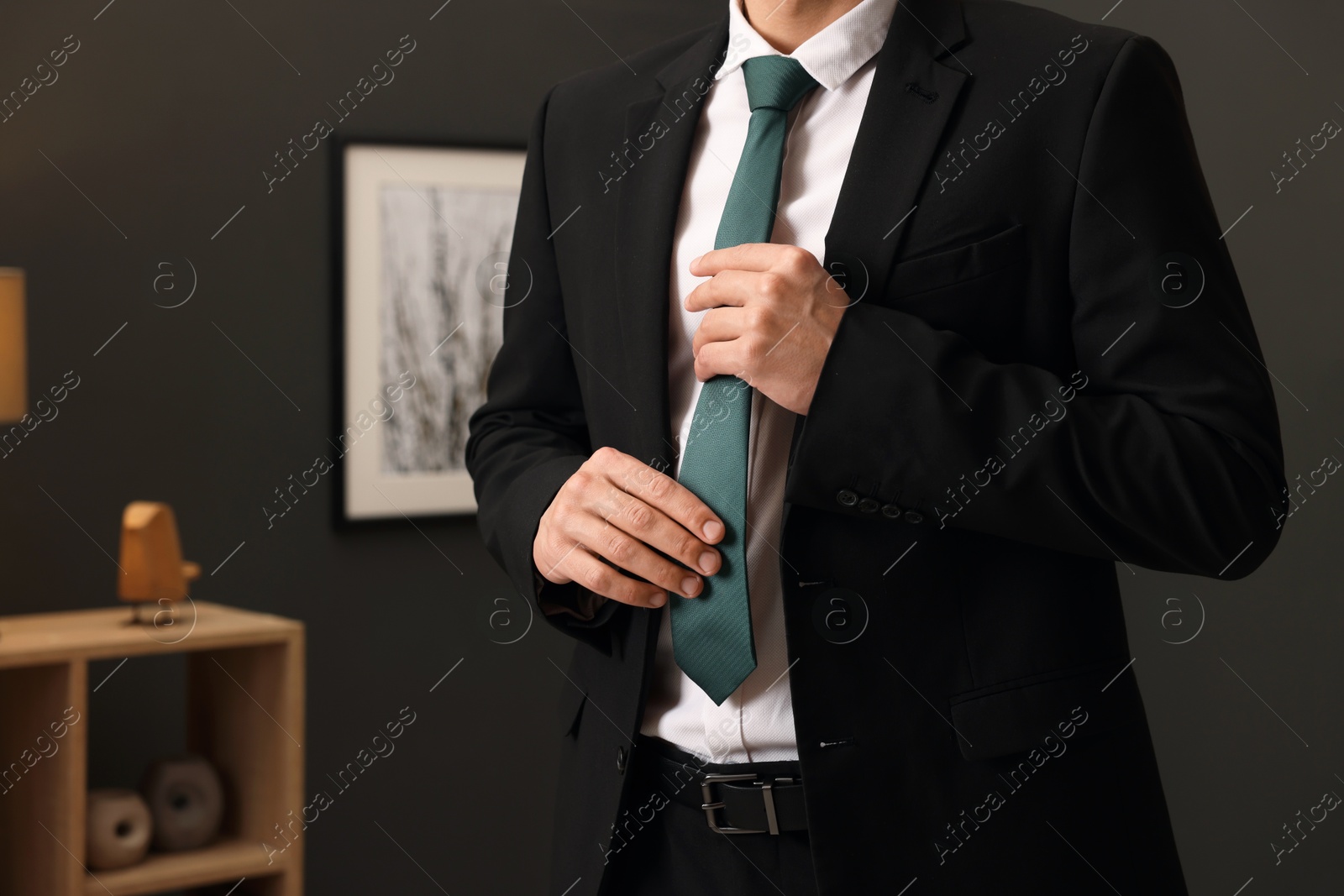 Photo of Man tying stylish necktie at home, closeup