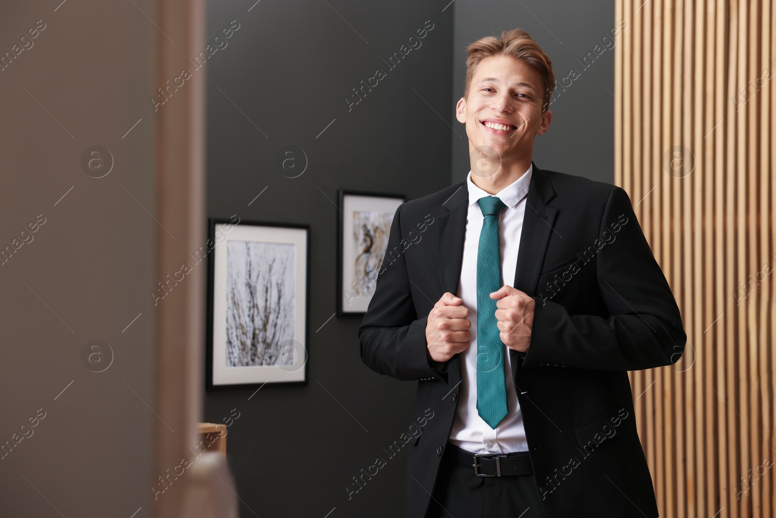 Photo of Man tying stylish green necktie at home