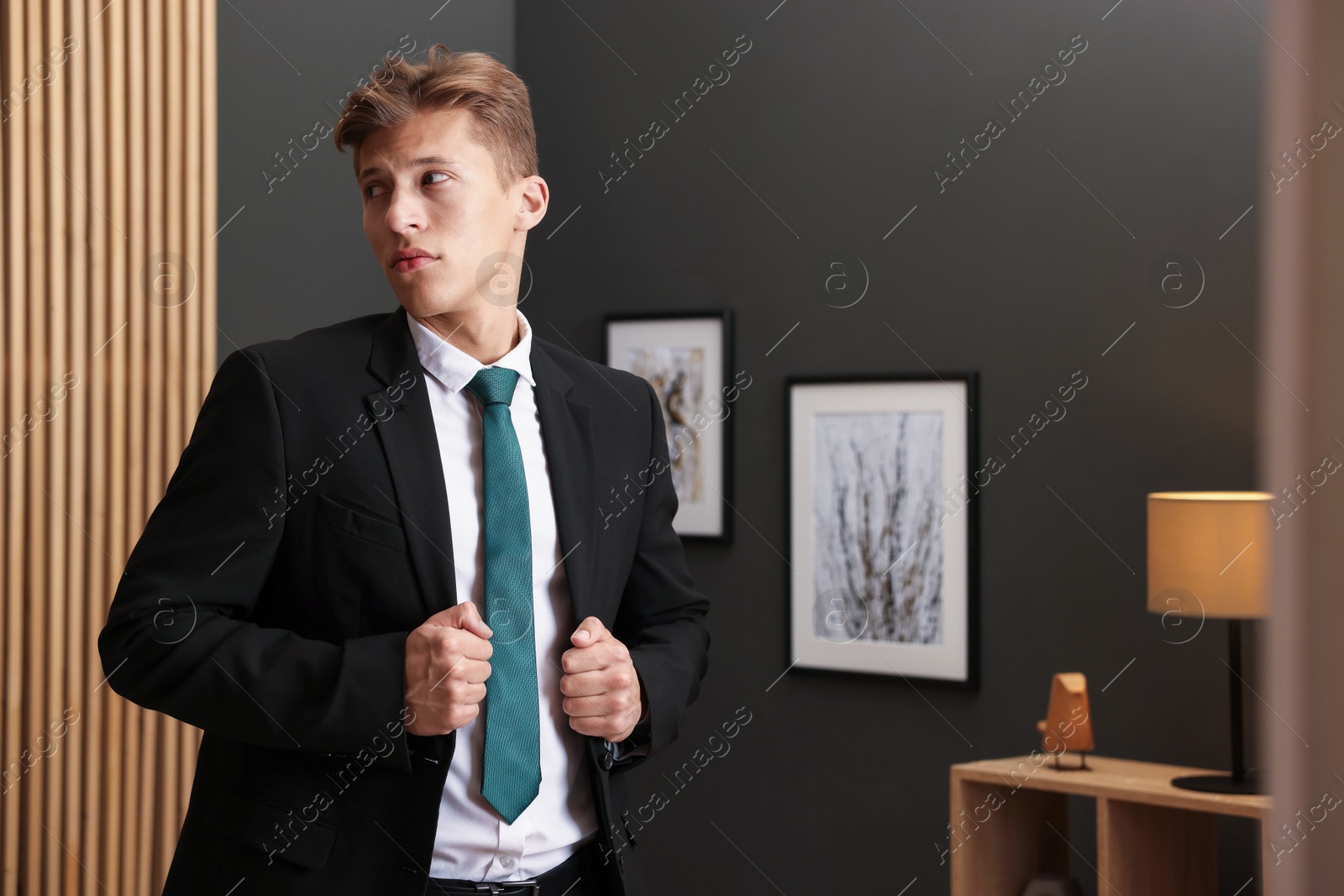 Photo of Man tying stylish green necktie at home