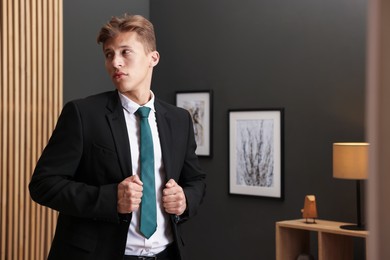 Photo of Man tying stylish green necktie at home