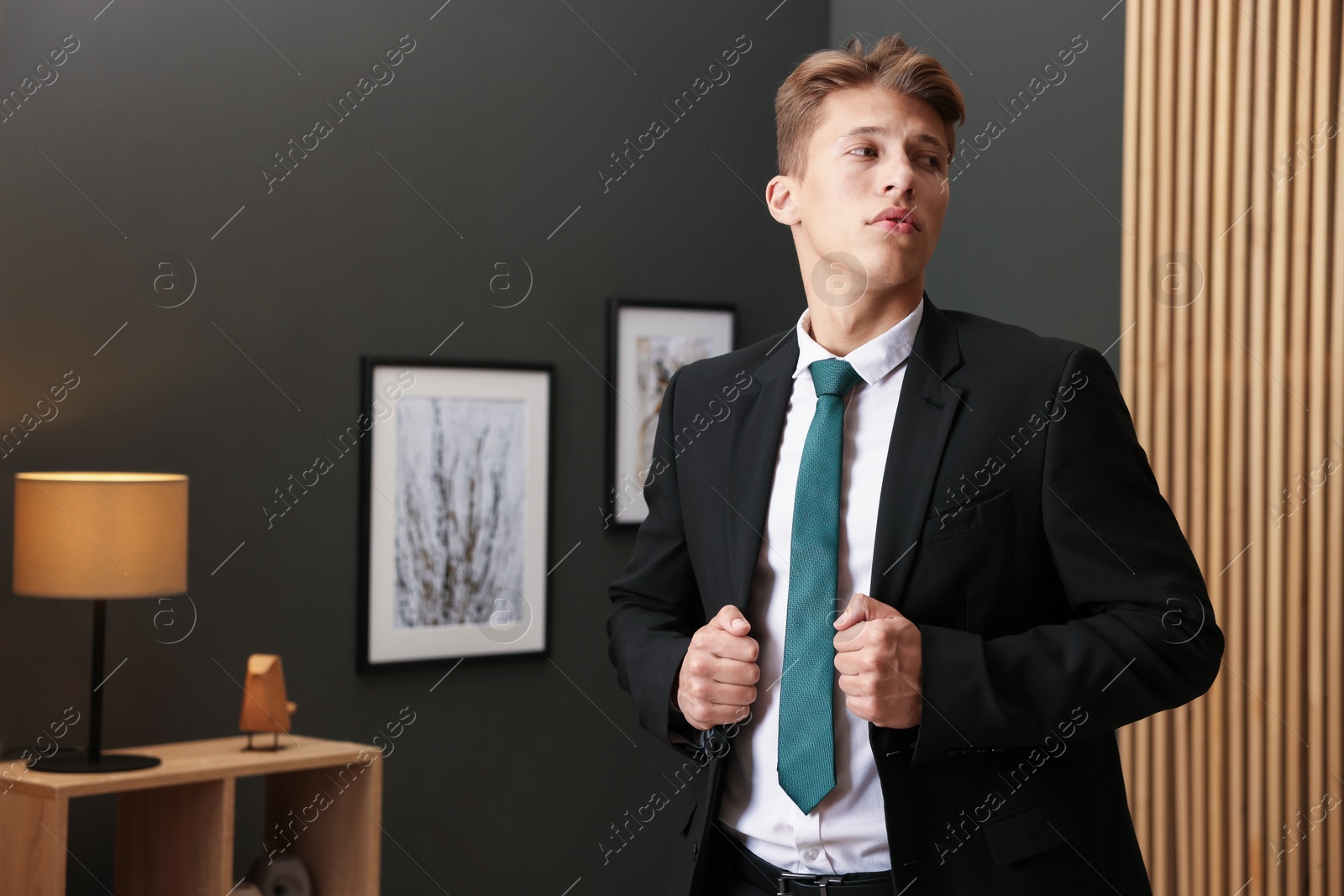 Photo of Man tying stylish green necktie at home