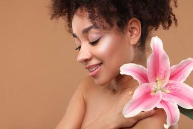 Photo of Portrait of beautiful Brazilian woman with lily flower after spa treatment on light brown background, closeup