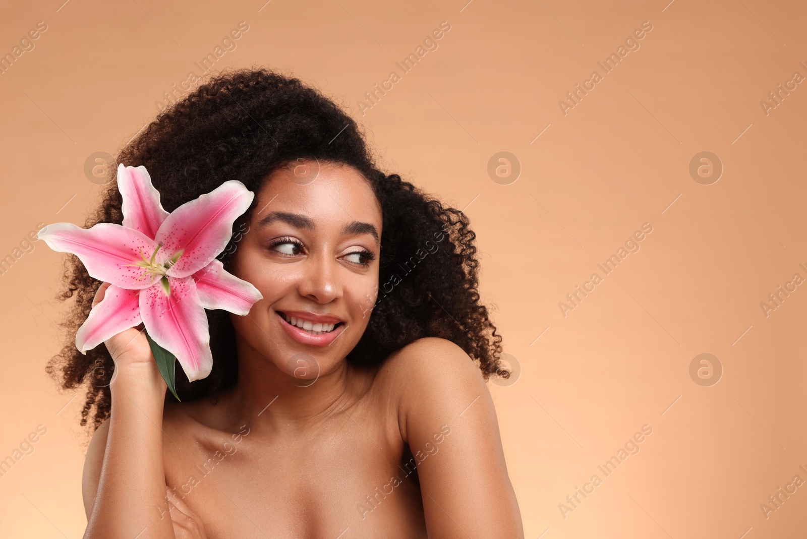 Photo of Portrait of beautiful Brazilian woman with lily flower after spa treatment on beige background. Space for text