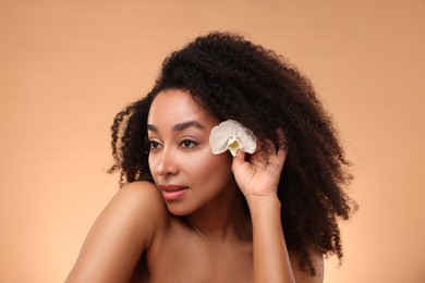 Photo of Portrait of beautiful Brazilian woman with orchid flower after spa treatment on beige background