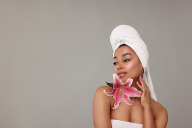 Photo of Portrait of beautiful Brazilian woman with lily flower after spa treatment on gray background. Space for text