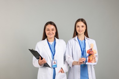 Photo of Medical students with human body model and clipboard on light grey background