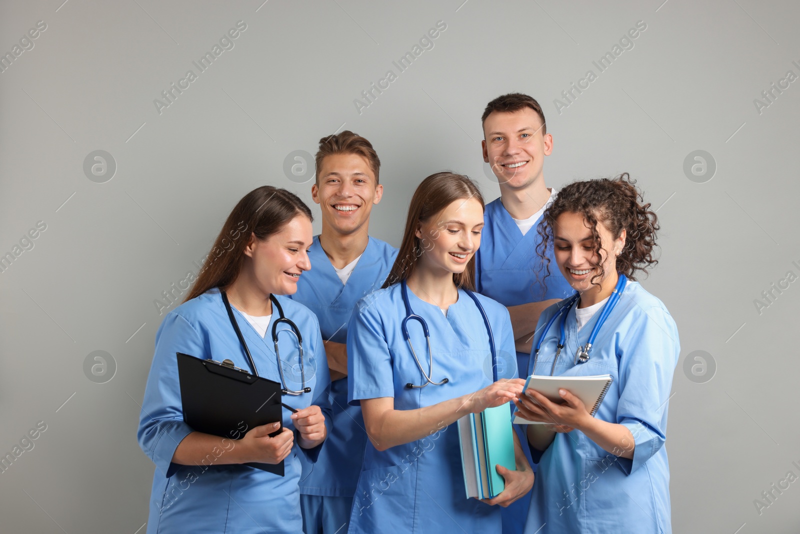 Photo of Group of medical students with books on light grey background