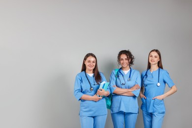 Photo of Group of medical students with books on light grey background. Space for text