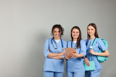 Photo of Group of medical students with tablet on light grey background. Space for text