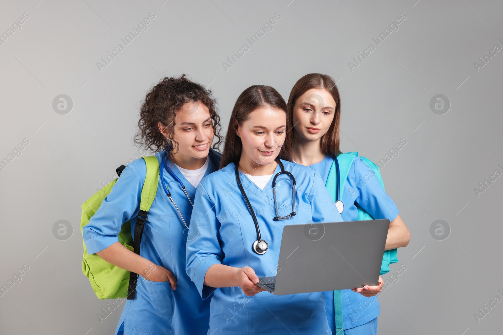 Photo of Group of medical students with laptop on light grey background