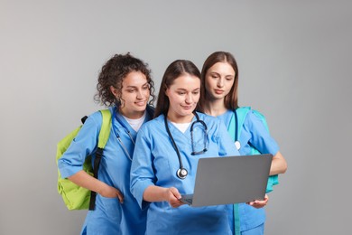 Photo of Group of medical students with laptop on light grey background