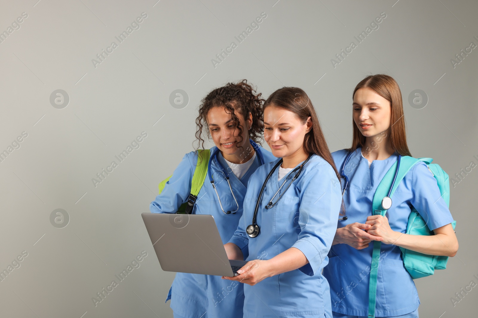 Photo of Group of medical students with laptop on light grey background. Space for text