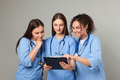 Photo of Group of medical students with clipboard on light grey background