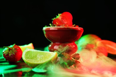 Photo of Hookah bowl with limes, strawberries, mint and smoke on black table, closeup