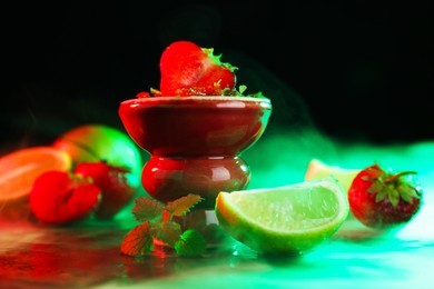 Photo of Hookah bowl with limes, strawberries, mint and smoke on black table, closeup