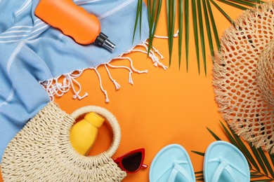 Photo of Frame of beach accessories and palm leaves on orange background, flat lay. Space for text