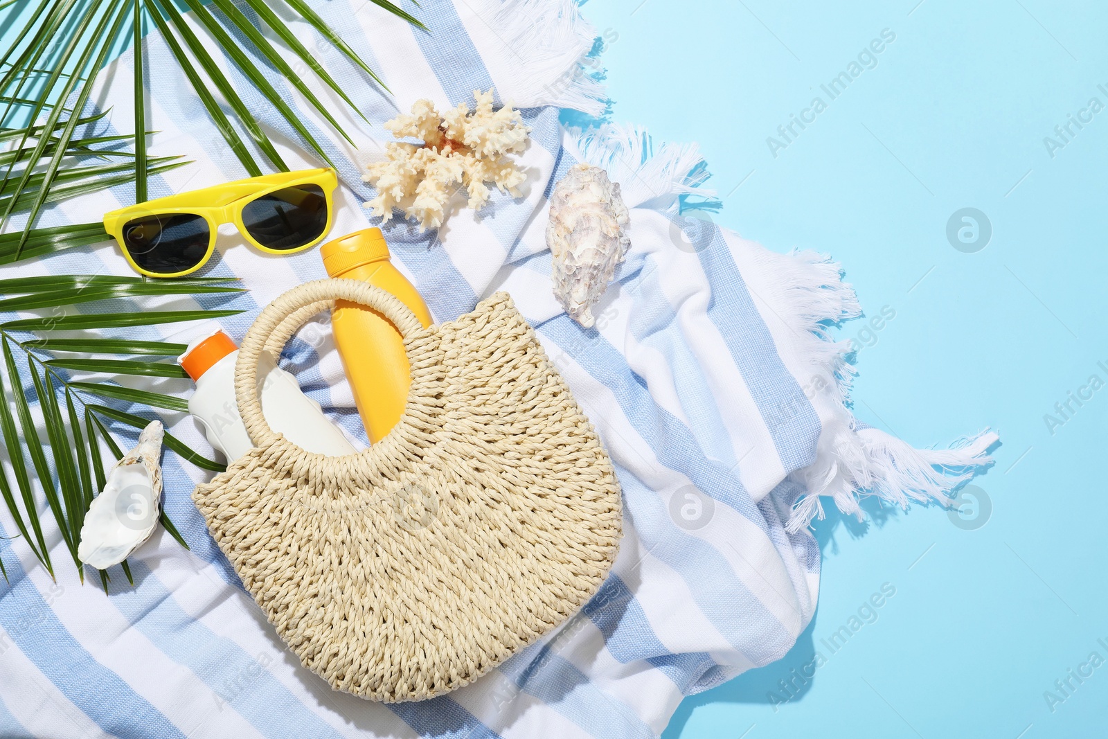 Beach accessories, sea shells and palm leaves on light blue background, flat lay Photo of Beach accessories, sea shells and palm leaves on light blue background, flat lay