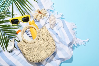 Photo of Beach accessories, sea shells and palm leaves on light blue background, flat lay